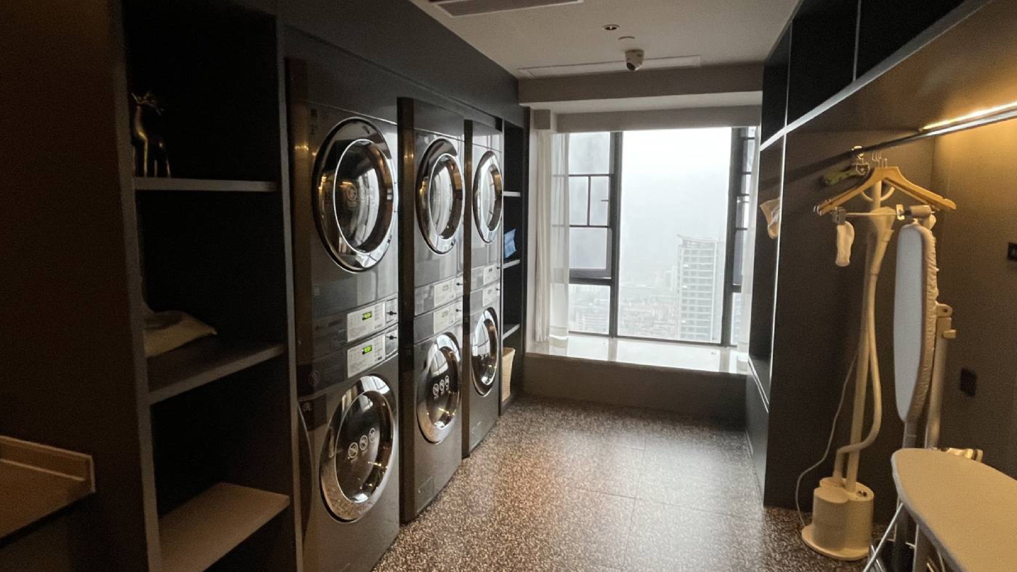 Typical laundry room in an Atour hotel. Stacked laundry machine and driers, with ironing boards and steamers available.